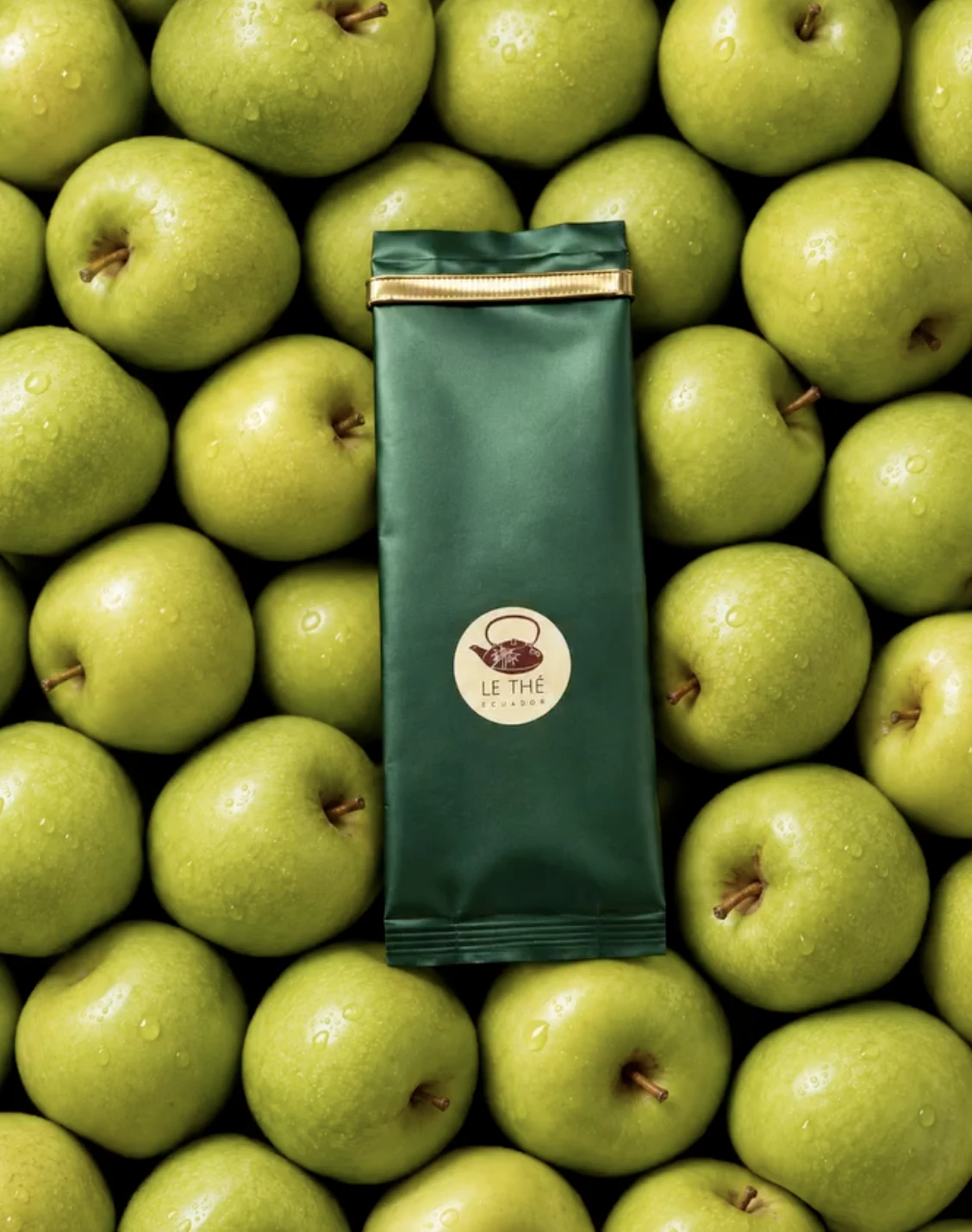 Empaque verde de Le Thé rodeado de manzanas verdes